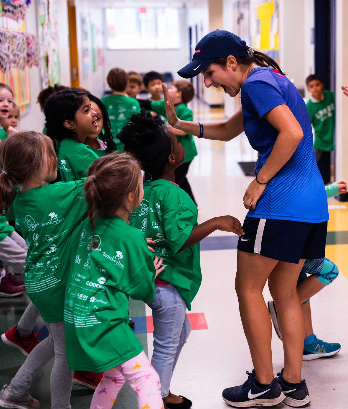 Booster team member high-fiving students in a school hallway